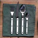 Set of silver cutlery with white handles on a green napkin