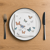 Butterfly-themed napkin on a plate with cutlery on a wooden table
