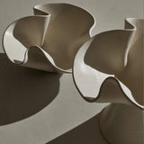Abstract sculpture with wavy, organic design on a neutral background
