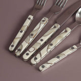 Set of silver cutlery with decorative handles on a purple background