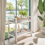 Bar cart with drinks and decor items in a room with large windows showing an outdoor view.