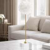 Decorative lamp on a marble coffee table with a beige sofa and curtains in the background