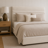Beige bedroom with a bed, nightstand, and lamp.