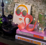 Pink flamingo ornament on books with a Dior magazine in the background