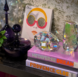 Decorative items including a black perfume bottle, crystal, and books on a reflective surface.