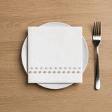 White plate with folded napkin and silver fork on a wooden table