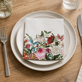Table setting with floral napkin, plates, cutlery, and a glass on a wooden table.