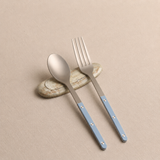 Spoon and fork with blue handles on a beige background
