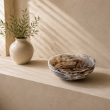 Ceramic bowl and vase on a beige surface with soft lighting